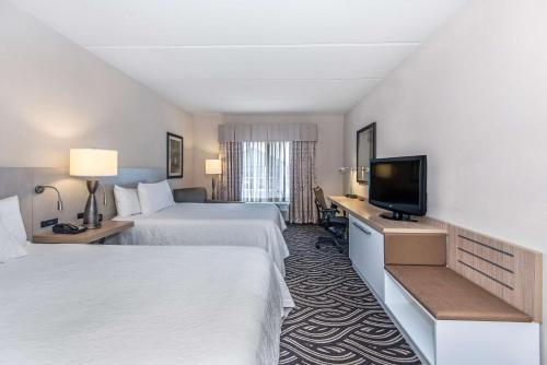 a hotel room with two beds and a flat screen tv at Hilton Garden Inn Charleston Airport in Charleston