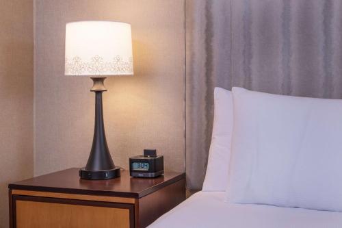 a bed with a lamp and a clock on a night stand at Hilton Wilmington/Christiana in Newark