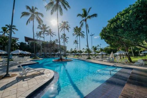 a large swimming pool with palm trees in a resort at Marulhos Resort - Flat e Studio in Porto De Galinhas