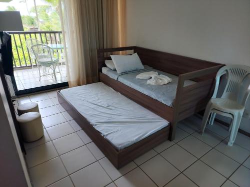 a bedroom with a bed and a chair and a balcony at Marulhos Resort - Flat e Studio in Porto De Galinhas
