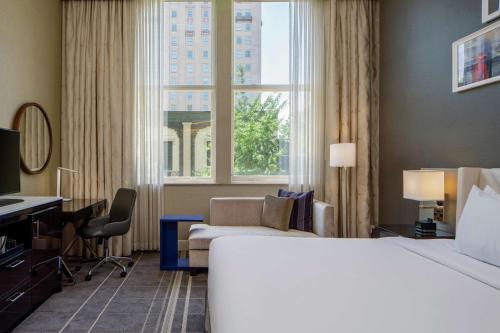 a hotel room with a bed and a desk and a window at Hilton Richmond Downtown in Richmond