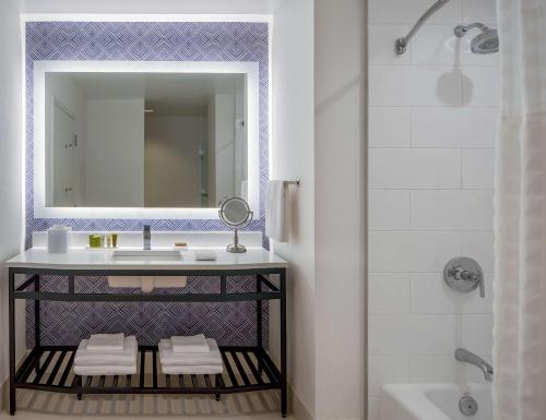 a bathroom with a sink and a mirror and a tub at Hilton Richmond Downtown in Richmond