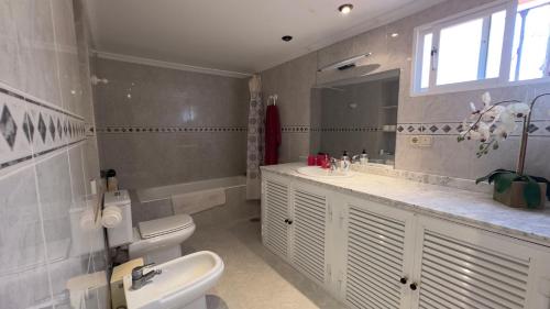 bagno con lavandino, servizi igienici e specchio di VILLA BELLAVISTA a Ceuta