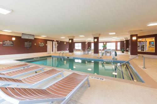 Homewood Suites by Hilton Bloomington في بلومنغتون: مسبح كبير مع كراسي في مبنى