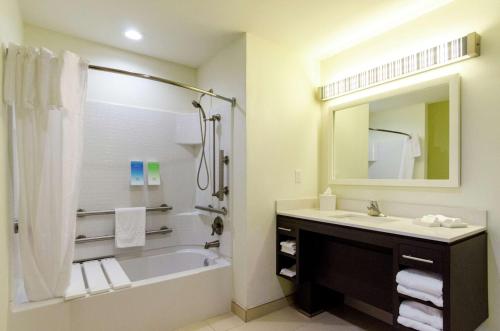a bathroom with a tub and a sink and a mirror at Home2 Suites by Hilton Portland in Portland