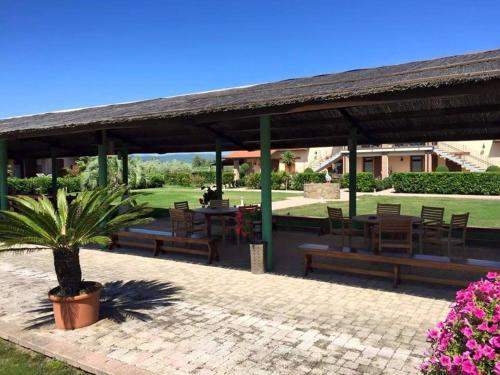 a pavilion with wooden benches and a table and chairs at Agriturismo Cannavota in Follonica