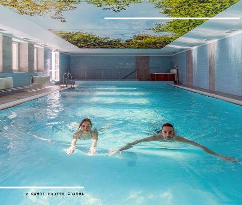 Ein Mann und eine Frau schwimmen im Pool in der Unterkunft Hotel Kamzík *** in Malá Morávka