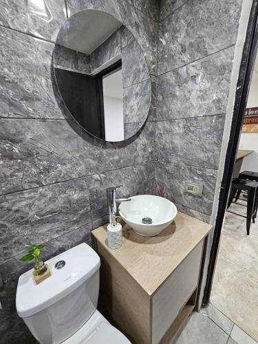 een badkamer met een wastafel, een toilet en een spiegel bij Apartamentos del Sur in Itagüí