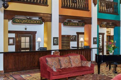 a living room with a red couch and a piano at Hotel Alex Johnson Rapid City, Curio Collection by Hilton in Rapid City