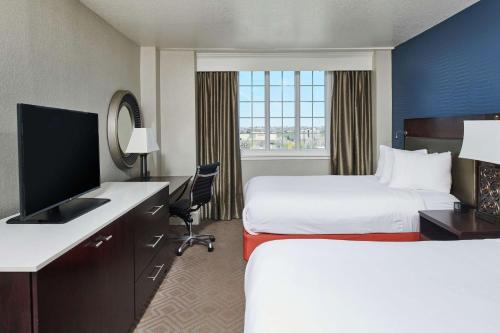 a hotel room with two beds and a television at Hotel Alex Johnson Rapid City, Curio Collection by Hilton in Rapid City