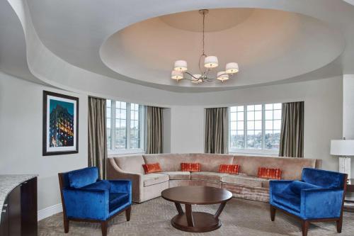 a living room with a couch and blue chairs at Hotel Alex Johnson Rapid City, Curio Collection by Hilton in Rapid City