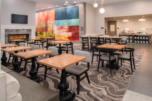 a dining room with tables and chairs and a fireplace at Homewood Suites By Hilton Belmont in Belmont