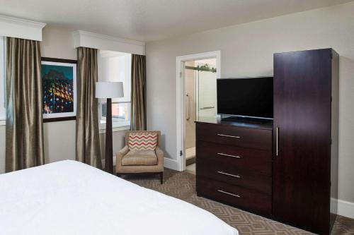 a hotel room with a bed and a flat screen tv at Hotel Alex Johnson Rapid City, Curio Collection by Hilton in Rapid City