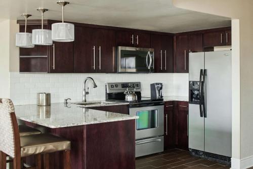 a kitchen with wooden cabinets and a white refrigerator at Hotel Alex Johnson Rapid City, Curio Collection by Hilton in Rapid City