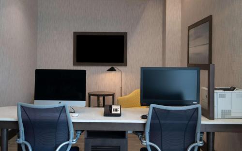 a room with a desk with two monitors and two chairs at Homewood Suites By Hilton North Charleston in Charleston