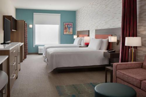 卡尔斯巴德Home2 Suites By Hilton Carlsbad New Mexico的有两张床和一把椅子的酒店房间