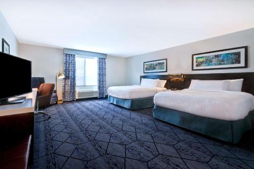 锡达拉皮兹Hilton Garden Inn Cedar Rapids的一间有两张床和一台平板电视的酒店房间