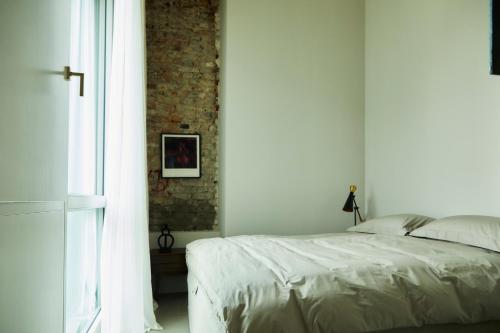 una camera con un letto bianco e un muro di mattoni di Stadtflucht Loft 5.2.2 a Berlino