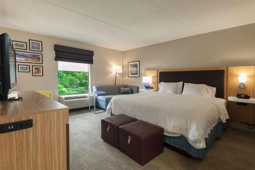a hotel room with a bed and a living room at Hampton Inn Doylestown in Warrington