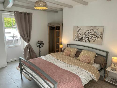 a bedroom with a large bed with a pink blanket at La part des Anges in Fontenet
