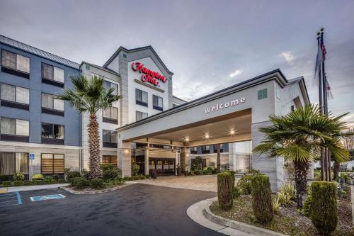 a hotel with palm trees in front of a building at Hampton Inn San Francisco Airport in South San Francisco