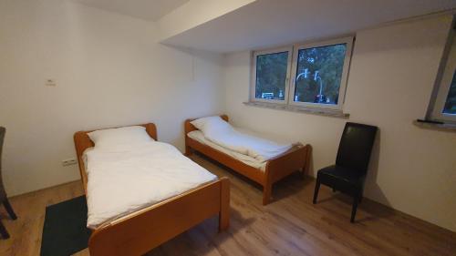 Habitación pequeña con 2 camas y silla en GreyGreen Residence I - Privates Bad, Gemeinschaftsküche und Aufenthaltsbereich, en Sehnde