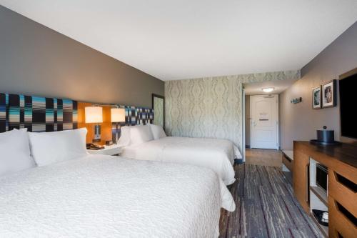 a hotel room with two beds and a television at Hampton Inn & Suites Herndon-Reston in Herndon