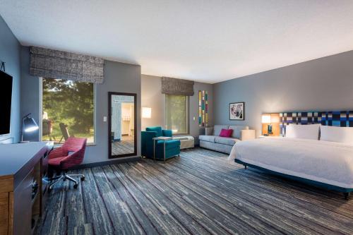a bedroom with a bed and a living room at Hampton Inn & Suites Herndon-Reston in Herndon