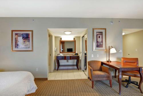 a bedroom with a bed and a desk and a bathroom at Hampton Inn and Suites Peoria at Grand Prairie in Peoria