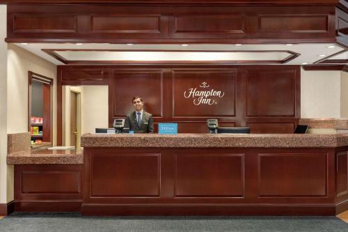 a man standing at a reception desk in a hotel lobby at Hampton Inn Dulles/Cascades in Sterling