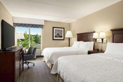 a hotel room with two beds and a flat screen tv at Hampton Inn Dulles/Cascades in Sterling