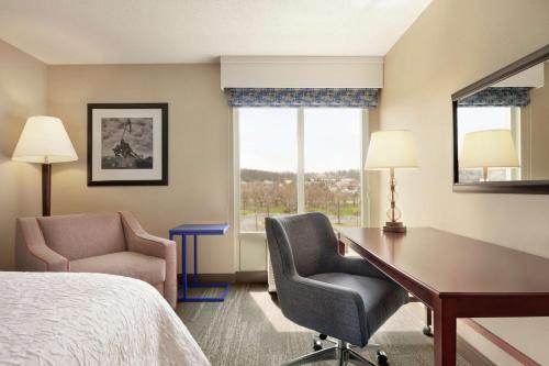 a hotel room with a desk and chair and a bed at Hampton Inn Dulles/Cascades in Sterling