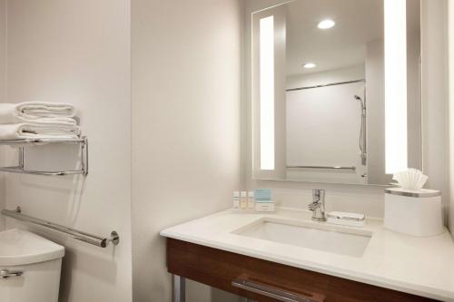a bathroom with a sink and a mirror and a toilet at Hampton Inn Dulles/Cascades in Sterling