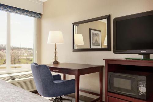 a hotel room with a desk and a television at Hampton Inn Dulles/Cascades in Sterling