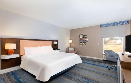 a hotel room with a large bed and a desk at Hampton Inn Corbin in Corbin