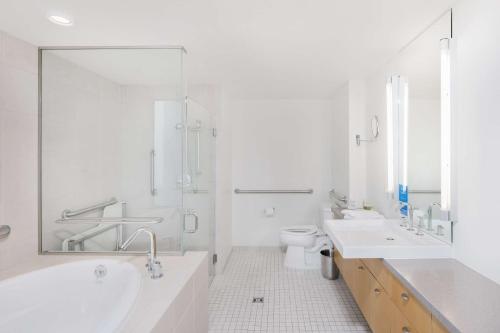 La salle de bains blanche est pourvue d'une baignoire, d'un lavabo et de toilettes. dans l'établissement Hotelvetro Iowa City, Tapestry Collection By Hilton, à Iowa City