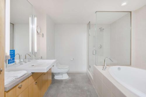 a bathroom with two sinks and a toilet and a shower at Hotelvetro Iowa City, Tapestry Collection By Hilton in Iowa City
