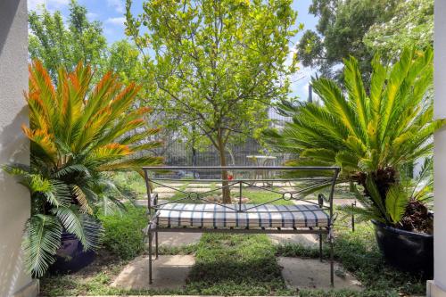 a bench in a garden with two plants at Solar Power French Country Cottage on Table Mountain in Cape Town