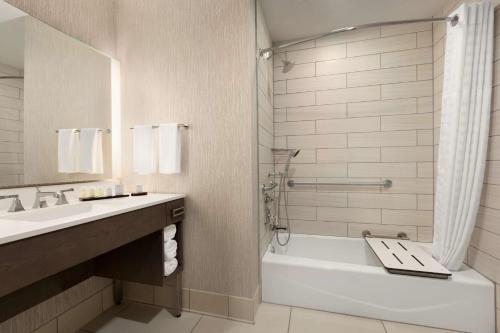 a bathroom with a tub and a toilet and a sink at Embassy Suites San Antonio Brooks City Base Hotel & Spa in San Antonio
