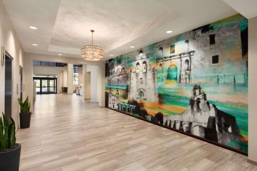 a hallway with a large painting on the wall at Embassy Suites San Antonio Brooks City Base Hotel & Spa in San Antonio