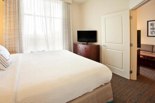 a bedroom with a white bed and a television at Residence Inn Baltimore Hunt Valley in Hunt Valley