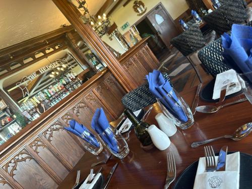 einen Tisch in einem Restaurant mit blauen Servietten und Küchenutensilien in der Unterkunft The Hedges Hotel in Stranocum