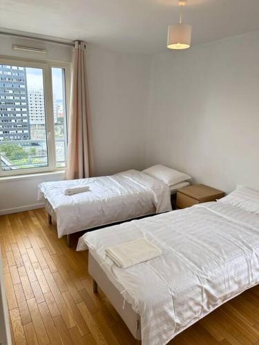 une chambre d'hôtel avec deux lits et une fenêtre dans l'établissement Magnifique Appart. spacieux 8P/ Défense-Courbevoie, à Courbevoie
