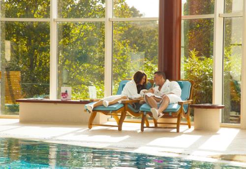 two people sitting at a table next to a pool at Seaham Hall and Serenity Spa in Seaham
