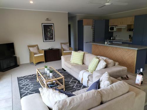a living room with two couches and a kitchen at Wildferns Lodge and Sailors Studio Opua in Opua