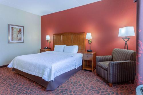 a hotel room with a bed and a chair at Hampton Inn Owings Mills in Owings Mills