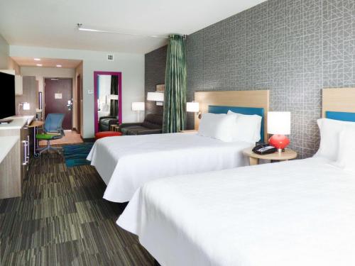 a hotel room with two beds and a living room at Home2 Suites By Hilton Pensacola I-10 Pine Forest in Pensacola