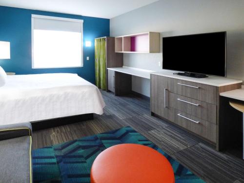 a hotel room with a bed and a flat screen tv at Home2 Suites By Hilton Pensacola I-10 Pine Forest in Pensacola