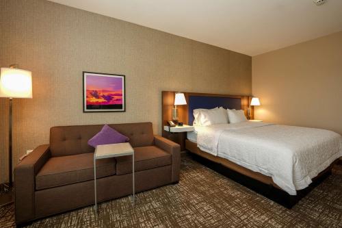 a hotel room with a bed and a couch at Hampton Inn & Suites Aurora South, Co in Aurora