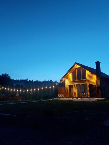 a house lit up at night with lights at Domki pod Bukowym lasem in Wańkowa